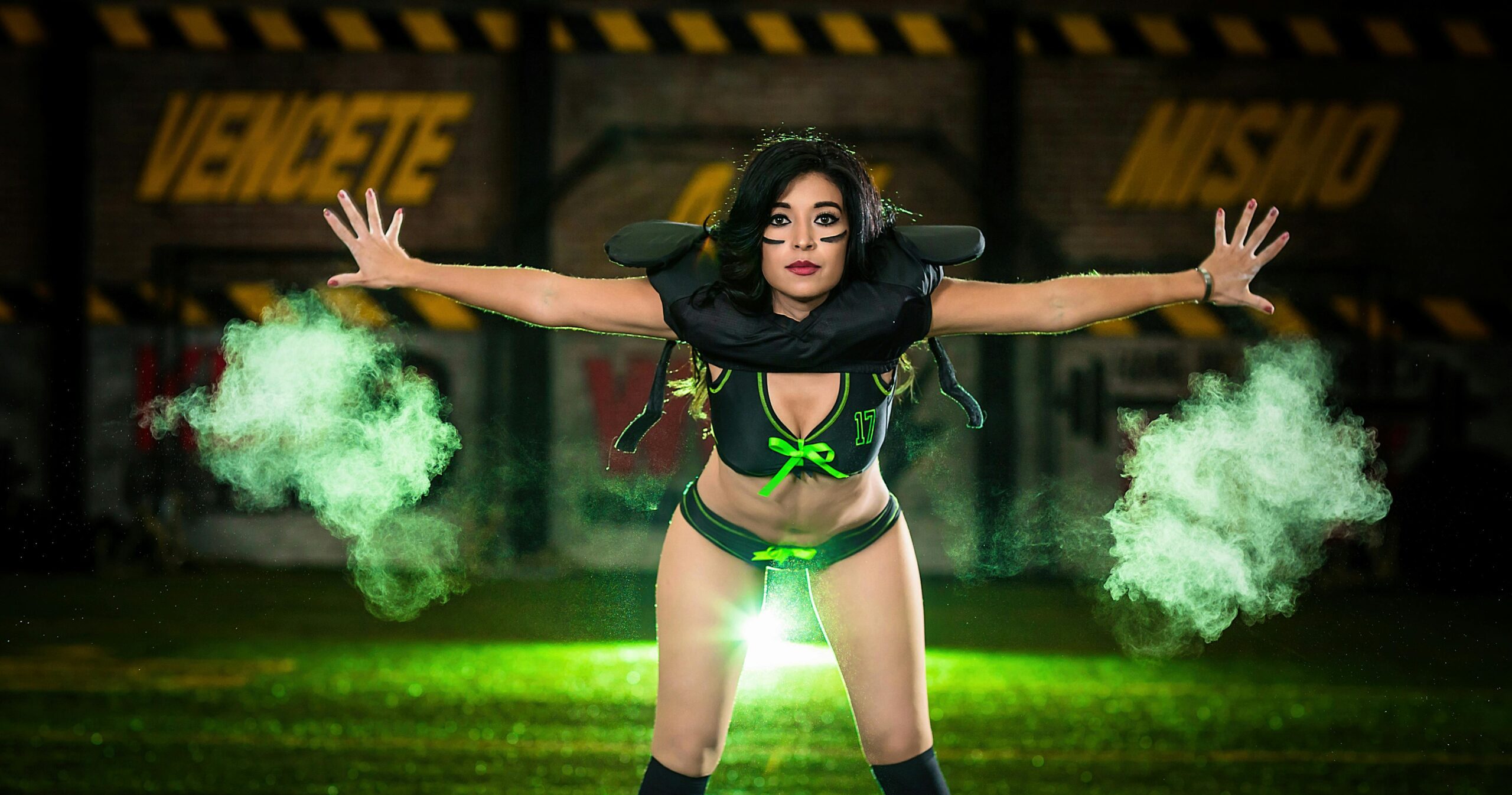 Dynamic portrait of a female performer in vibrant light and green smoke.