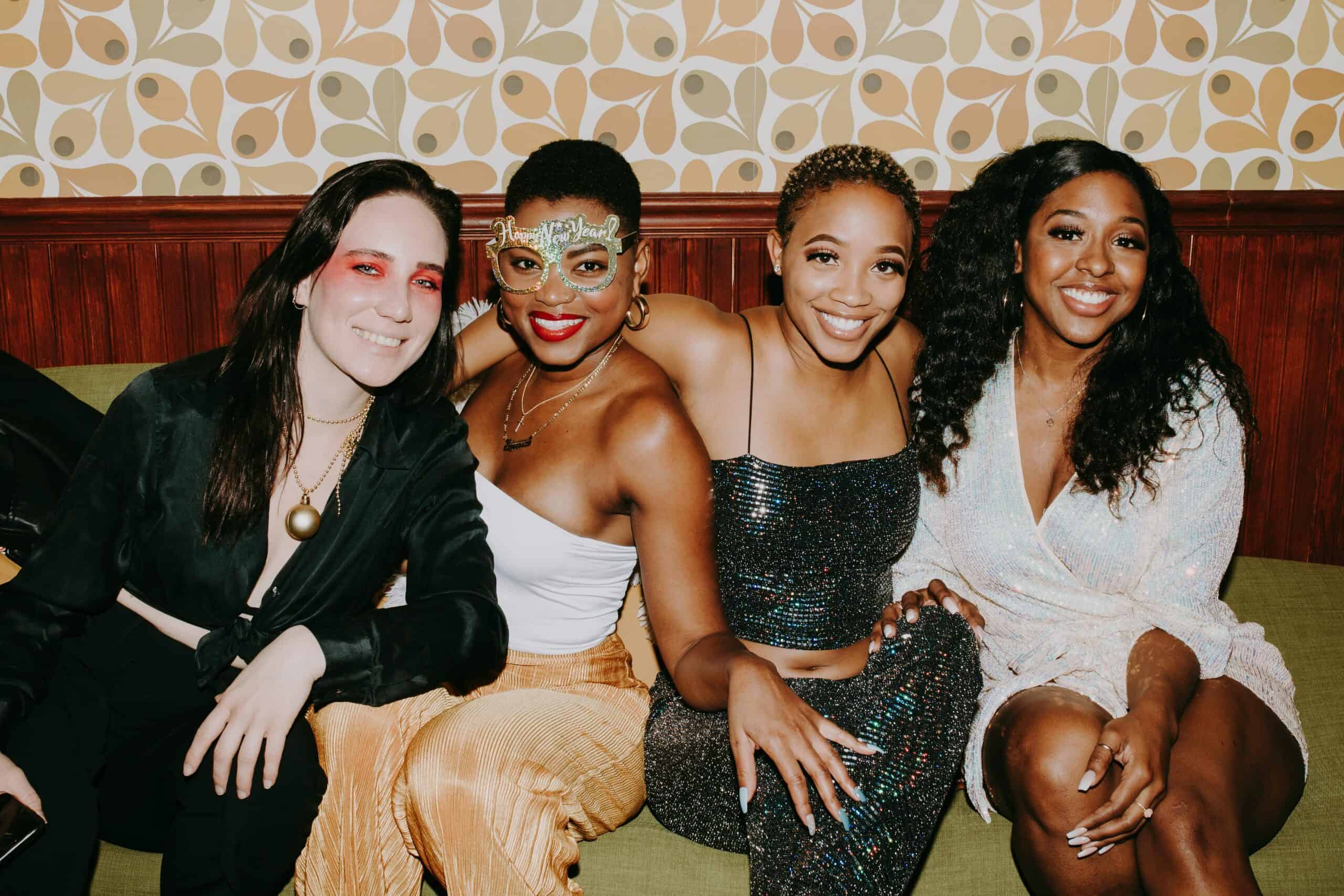 A lively group of friends in festive attire enjoying a New Year's celebration indoors.