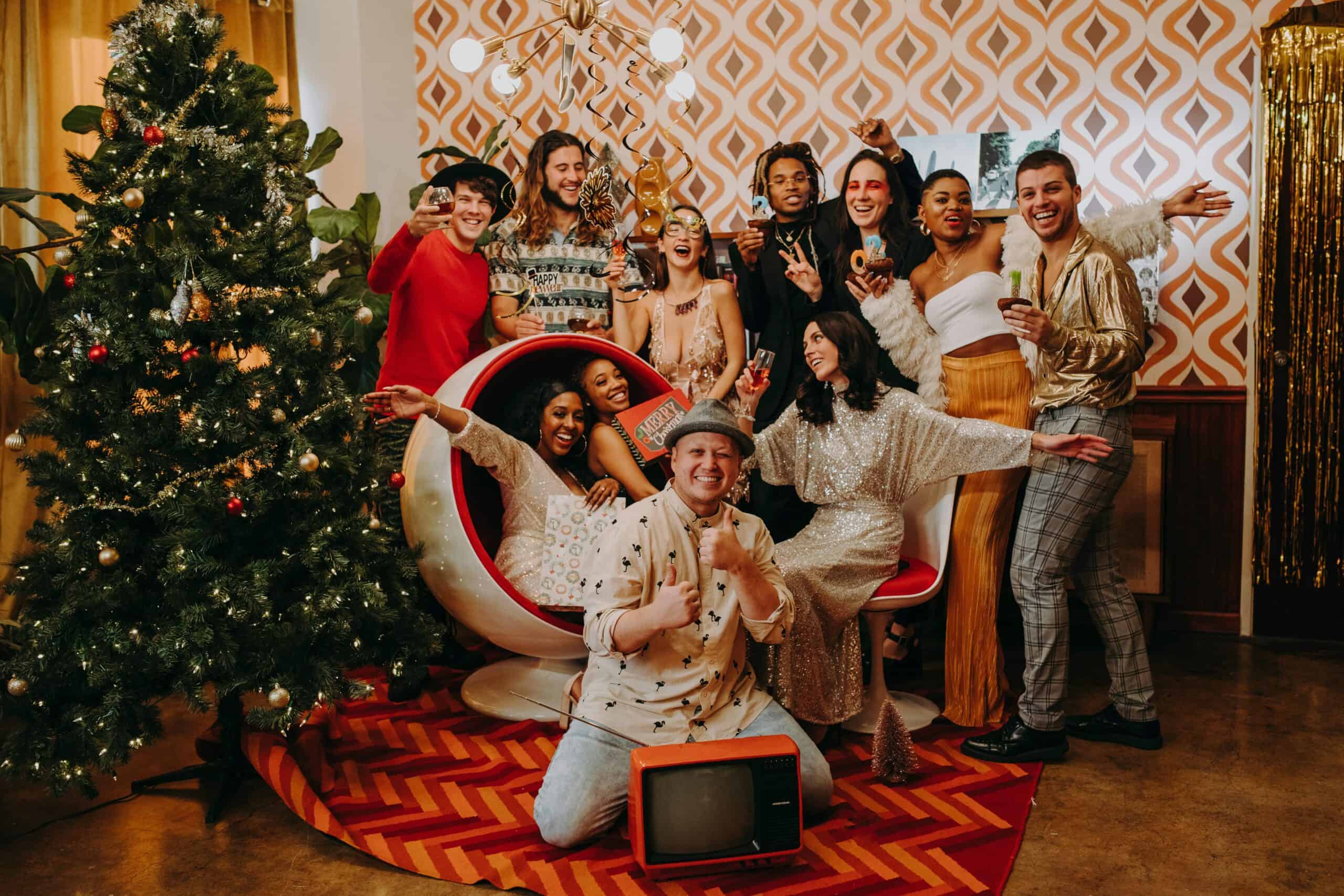 Group of friends celebrating Christmas with a cheerful indoor party, surrounded by festive decor.