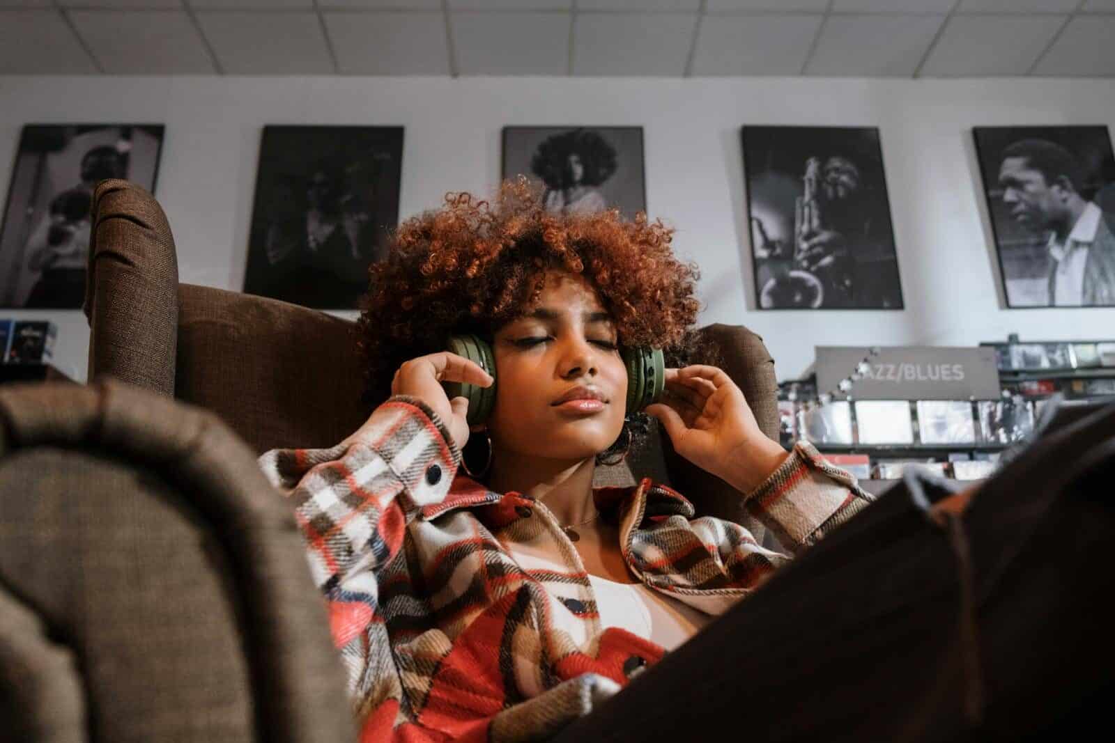 Young woman enjoying music with headphones in a cozy vintage setting.