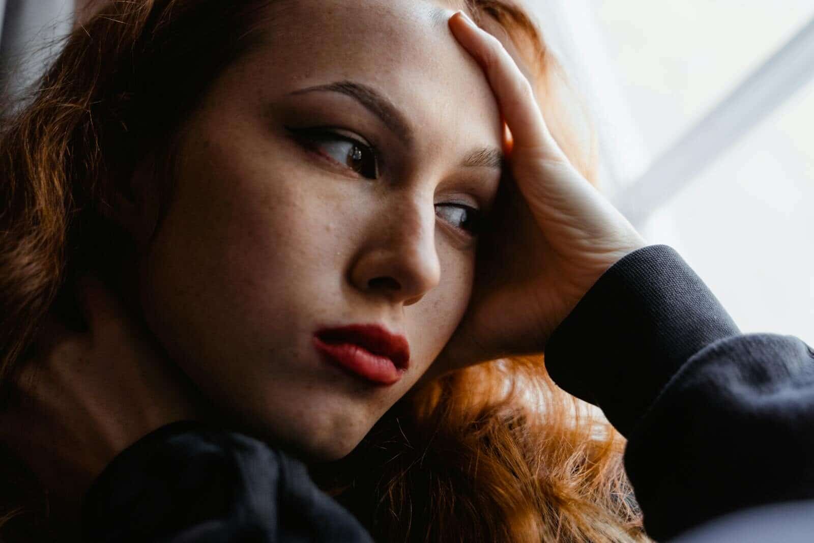 Close-up portrait of a pensive woman gazing out a window, reflecting deep thoughts and emotions.