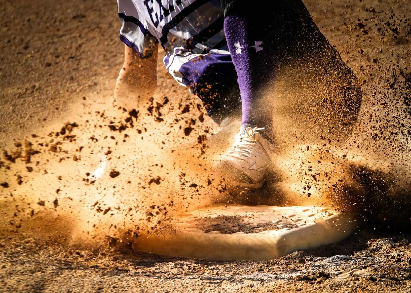 A baserunner slides into a base in a spray of dirt.